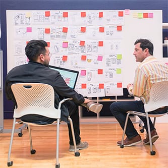 Two Ximedica San Francisco employees in a brainstorm meeting with a concept generation wall